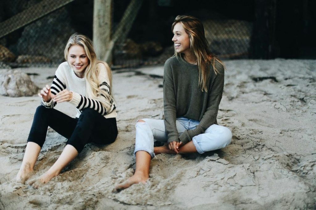 two people sitting on a beach under decking, how to stay positive