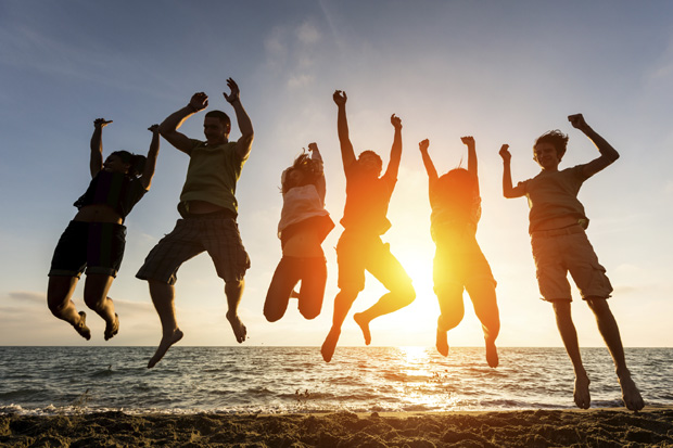 Friends jumping against a sunset on the beach